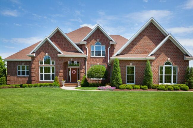 Elegant brick home with manicured lawn and landscaped garden, reflecting quality home maintenance and plumbing services.