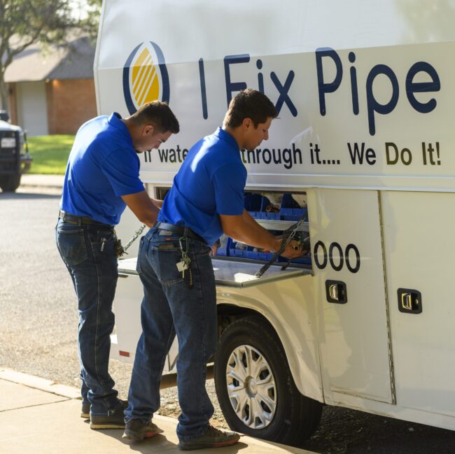Technicians from I Fix Pipe working on plumbing equipment in service vehicle, emphasizing modern plumbing solutions and professional service.