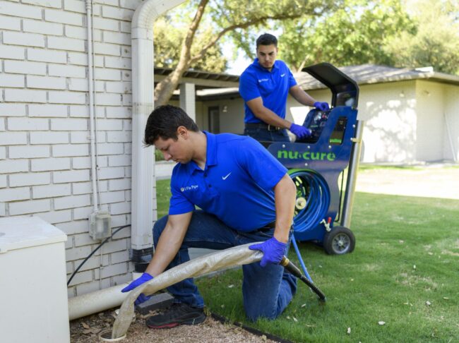 Technicians from I Fix Pipe using trenchless technology equipment for pipe repair outside a residential building in Odessa, TX.