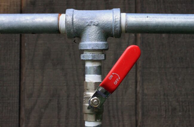 Plumbing valve with a red handle indicating on/off position, essential for home plumbing maintenance and repairs.
