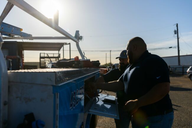 Two plumbers working on a service truck, showcasing tools and equipment for plumbing services in Odessa and Midland, Texas.