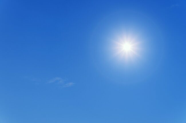 Bright sun shining in a clear blue sky, symbolizing summer heat impacting plumbing systems.