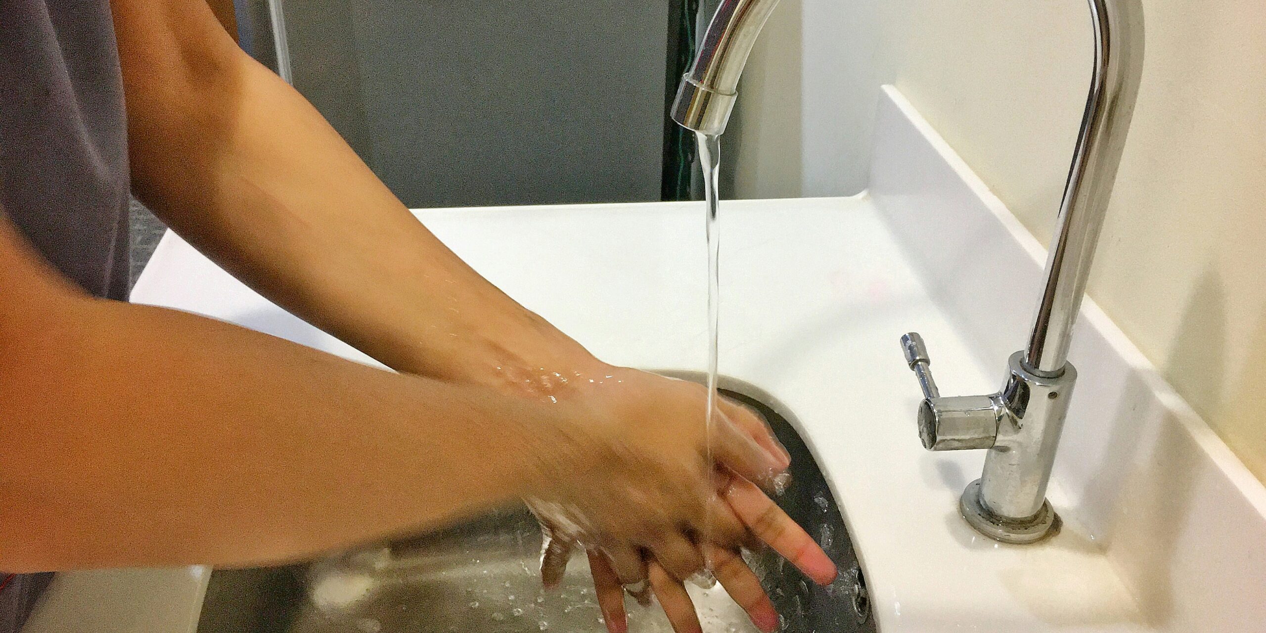 a person washing their hands under a running sink