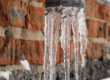 an exposed outdoor pipe with icicles hanging from it