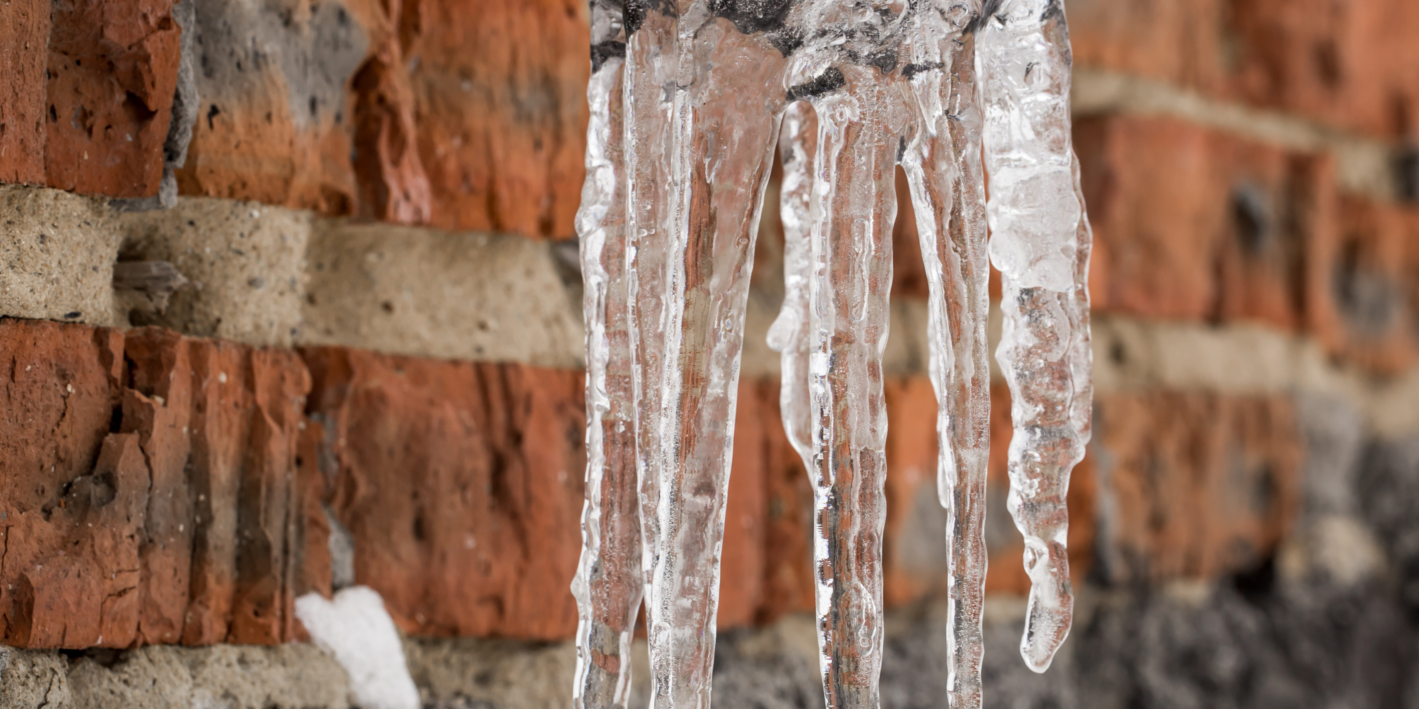 an exposed outdoor pipe with icicles hanging from it
