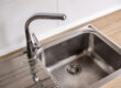 A stainless steel kitchen sink, focused on the drain