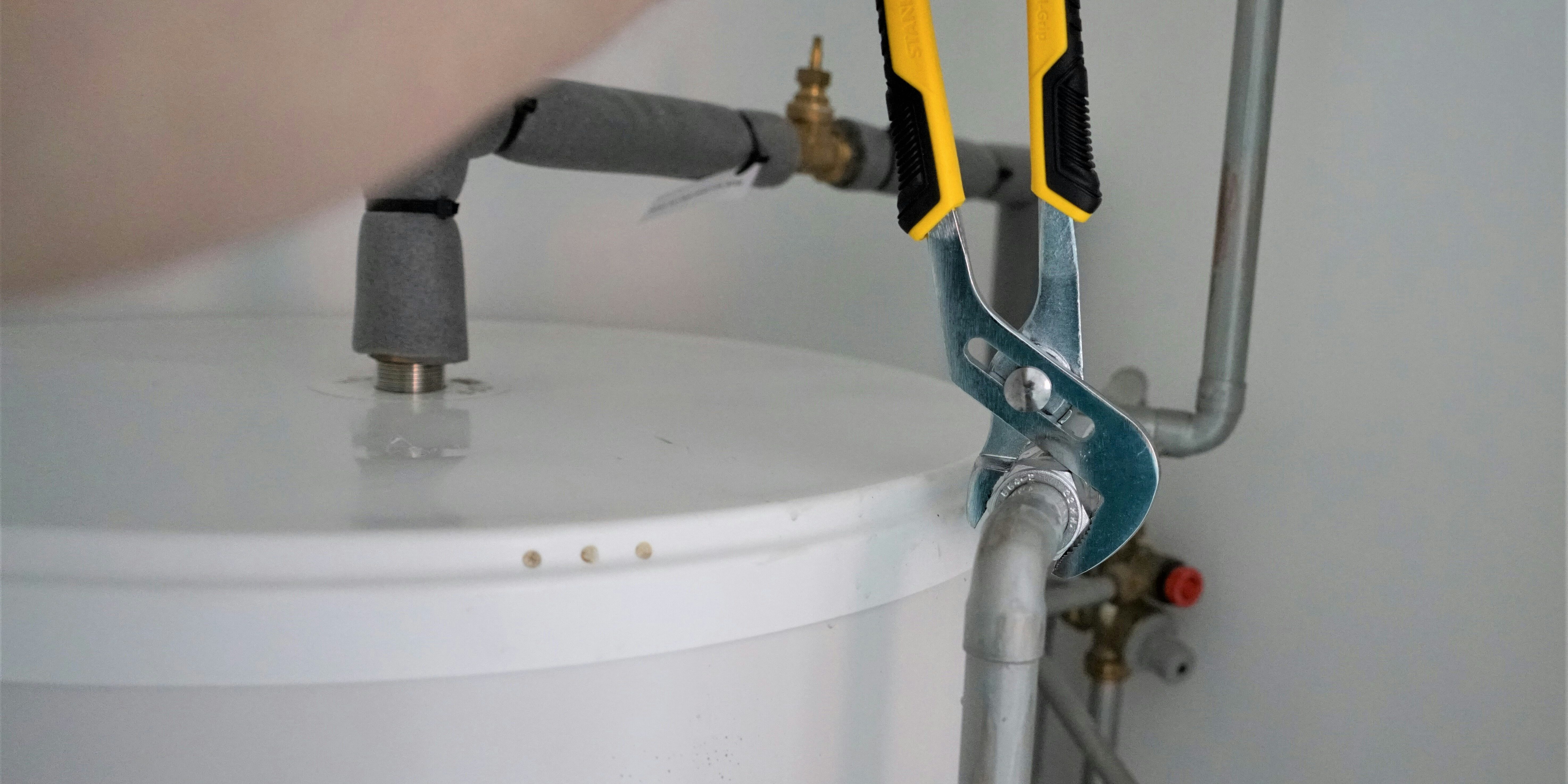 a man fixing a water heater with a wrench