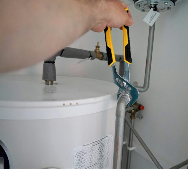 a man fixing a water heater with a wrench